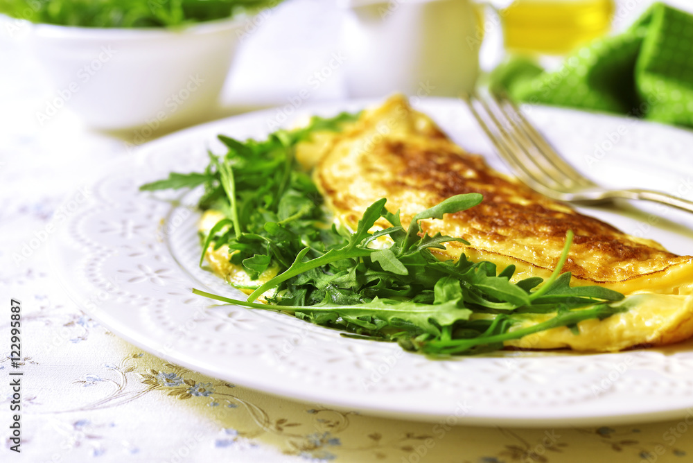 Omelet with cheese and arugula on a white plate. Omelet with cheese and arugula on a white plate.