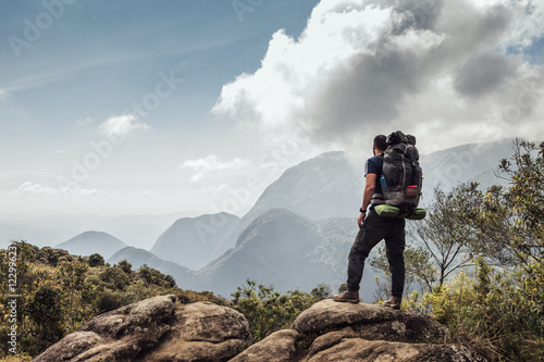 Male backpacker standing on mountain against sky photo