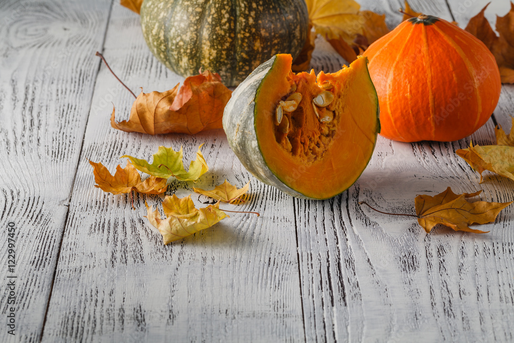 colorful pumpkin with stem and leaves on white wooden background Stock