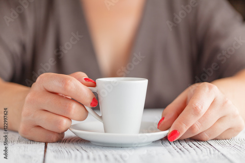Cup of coffee in the women's hand on table