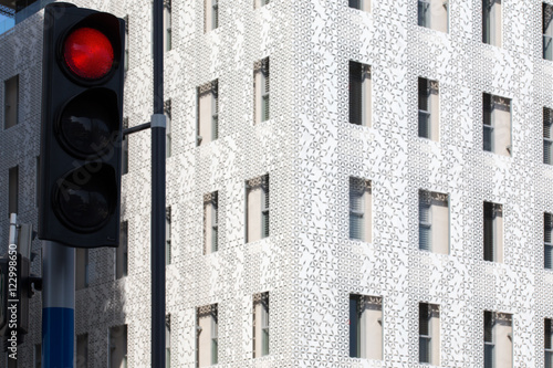 un feu rouge devant un building moderne  et blanc aux multiples fenêtres