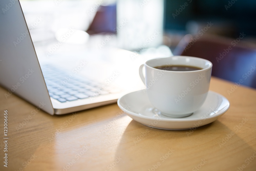 Close -up of cup of coffee and laptop on table Close -up of cup of coffee and laptop on table