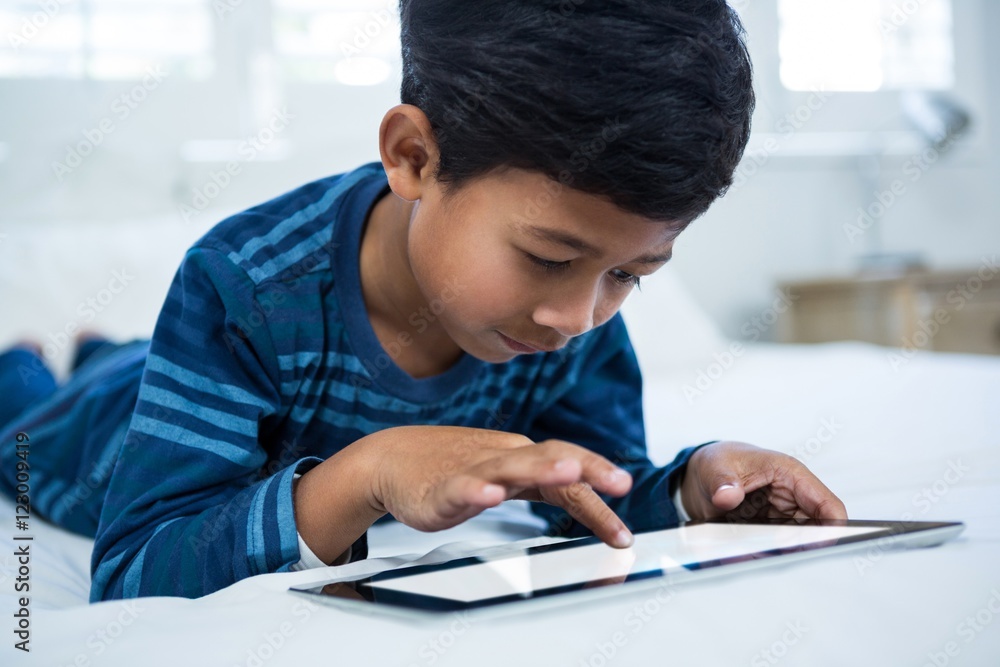Boy using digital tablet while relaxing on bed Boy using digital tablet while relaxing on bed