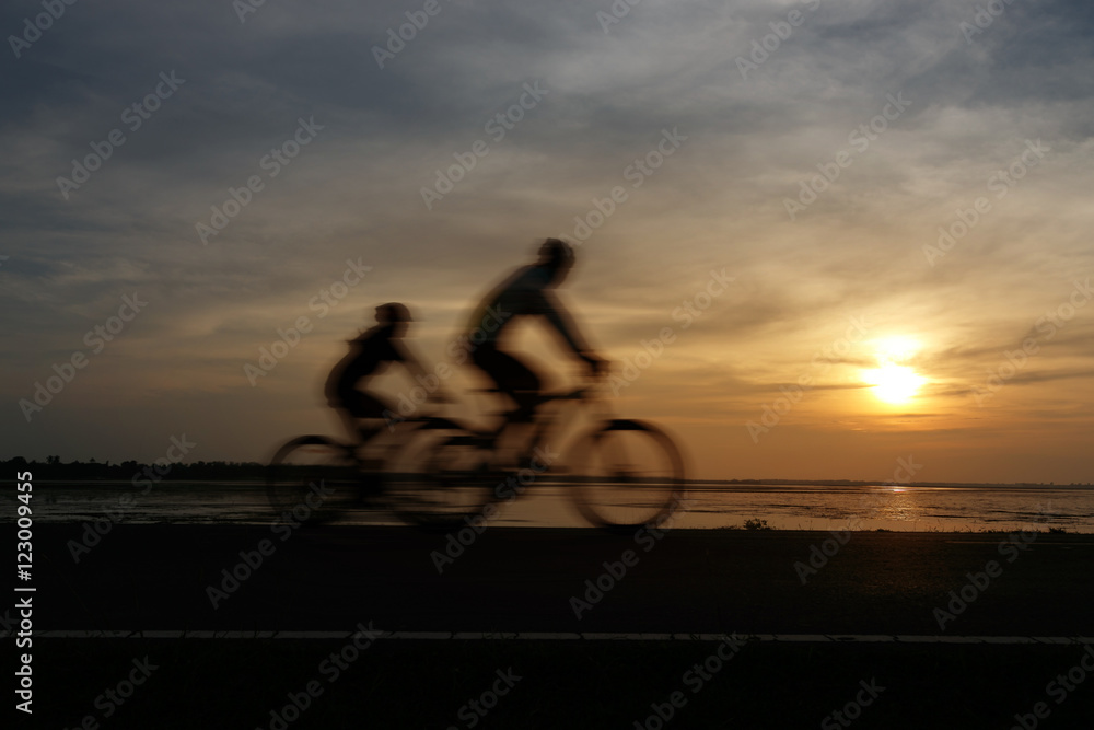 Fototapeta premium Silhouette ride bicycle at sunset. With effect subject movement