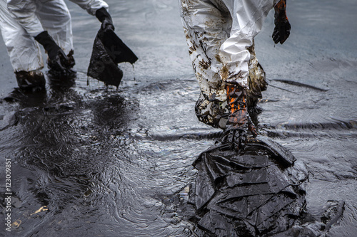 Workers remove crude oil from a beach photo