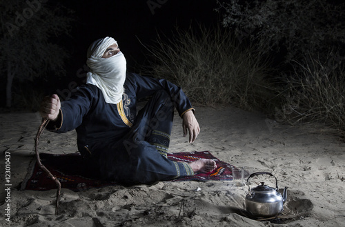 Tuareg man in a desert, making tea photo