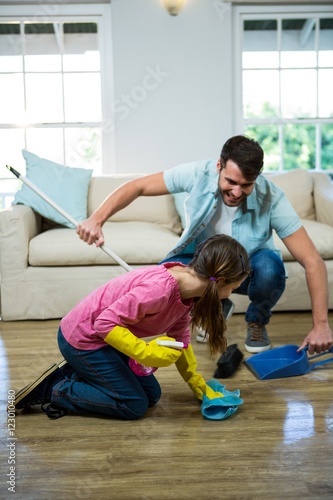 Daughter helping father to clean floor