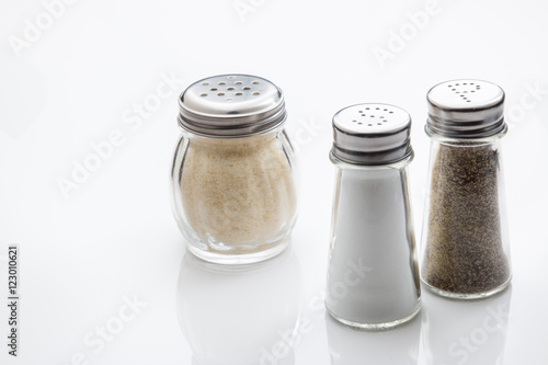 Salt, pepper and grated parmesan cheese in glass shakers.