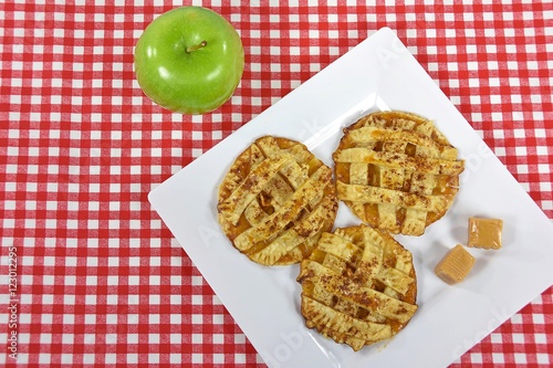 apple pie cookies and caramel candy on white square plate with green apple