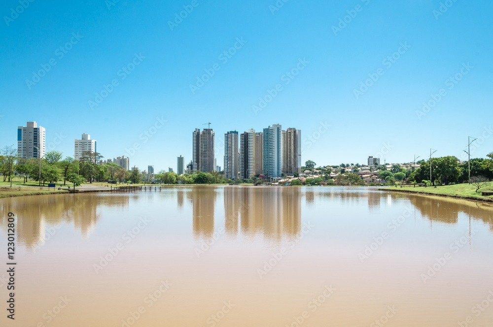 A beautiful sunny day at the lake with buildings and the city background. Scene reflected on water. Landscape from Park of Indigenous Nations in the city of Campo Grande MS, Brazil.