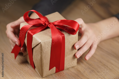 Fototapeta Naklejka Na Ścianę i Meble -  female teen girl shows paper gift box with red ribbon and a bow