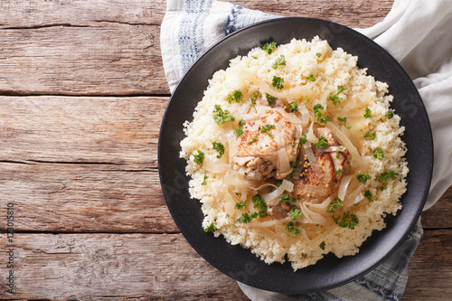 Yassa chicken with onions and garnished with couscous closeup. horizontal top view