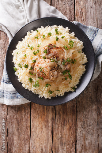 Yassa chicken with onions and garnished with couscous closeup. Vertical top view
