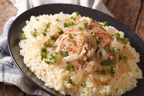 Yassa chicken stewed with marinated onions and couscous close up. horizontal

