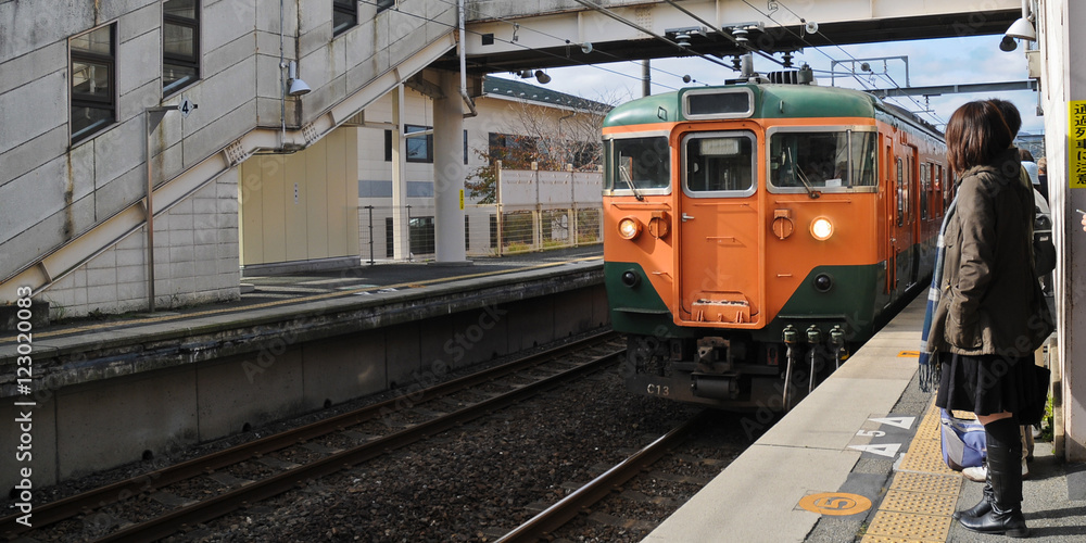 Fototapeta premium Orange vintage lowspeed local train approaching the platform