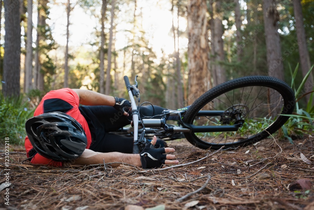 Fototapeta premium Male mountain biker fallen from his bicycle in the forest 