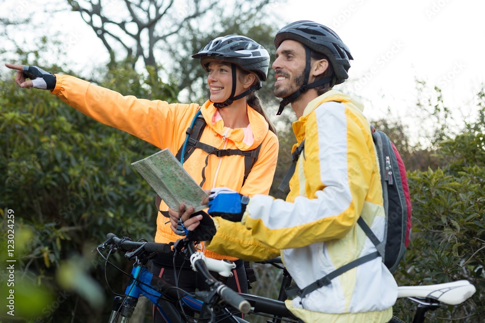 Fototapeta premium Biker couple with a map pointing in distance