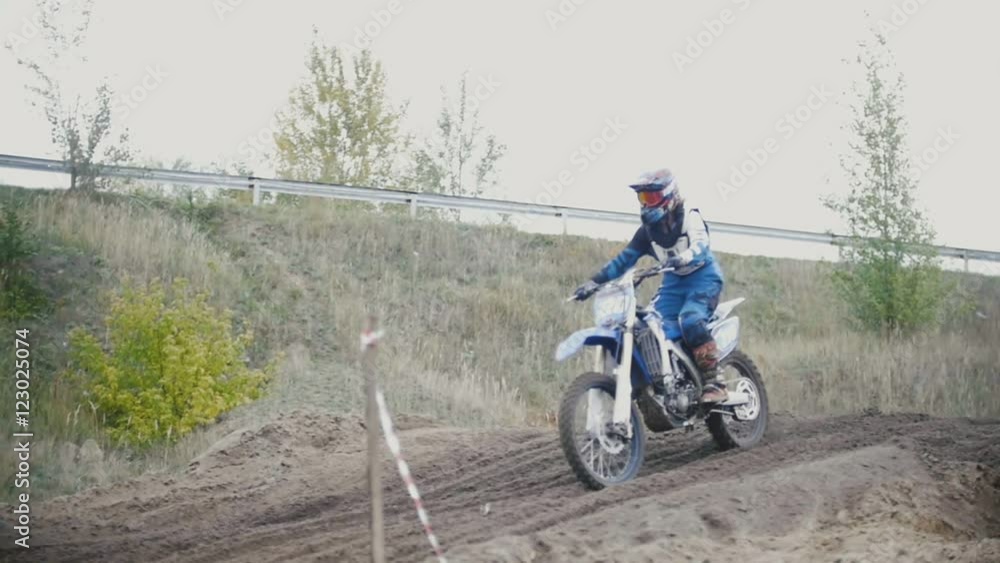 Motocross racer biker in blue jumpsuit jumping on track in rapid shoot, slow motion Motocross racer biker in blue jumpsuit jumping on track in rapid shoot, slow motion