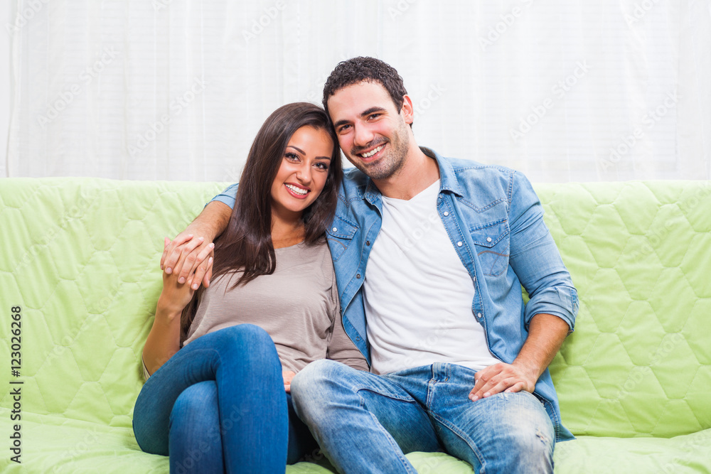 Happy couple sitting on sofa at their home.
