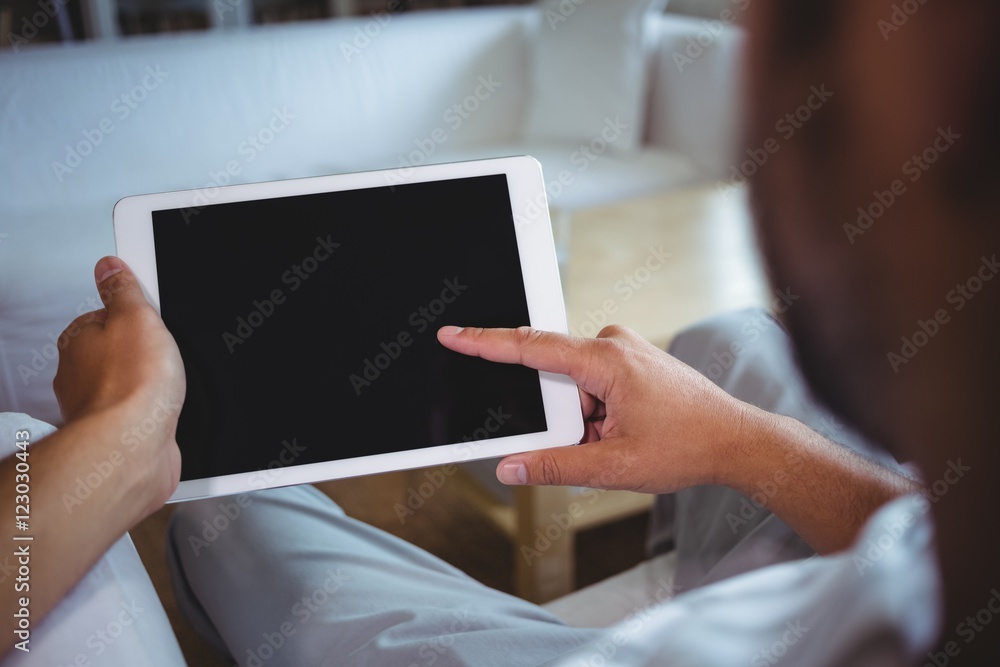 Mid section of man using digital tablet in living room Mid section of man using digital tablet in living room
