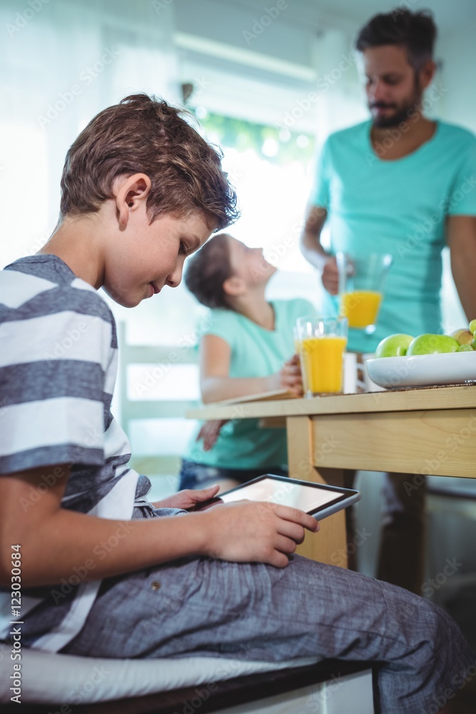 Boy using digital tablet with breakfast on table