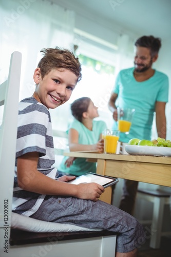 Boy using digital tablet with breakfast on table