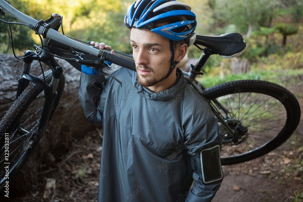 Male mountain biker carrying bicycle in the forest Male mountain biker carrying bicycle in the forest