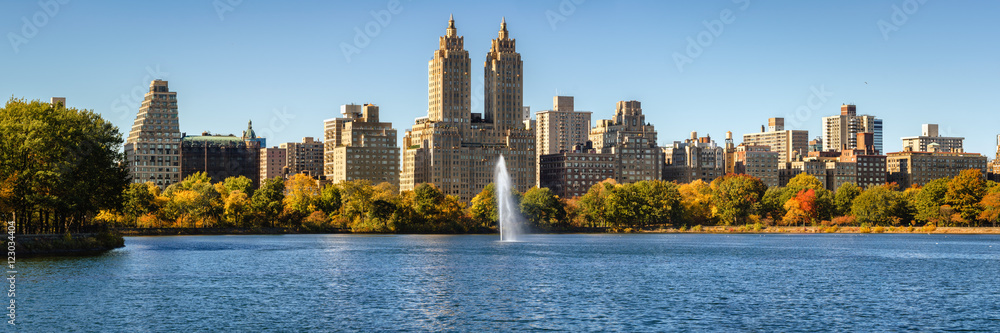 Central Park and Manhattan Upper West Side with colorful Fall foliage and a panoramic view across Jacqueline Kennedy Onassis Reservoir with its fountain. Central Park West in autumn. New York City Central Park and Manhattan Upper West Side with colorful Fall foliage and a panoramic view across Jacqueline Kennedy Onassis Reservoir with its fountain. Central Park West in autumn. New York City