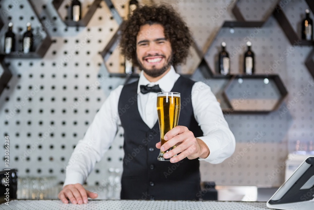 Bartender holding glass of beer in bar counter Bartender holding glass of beer in bar counter