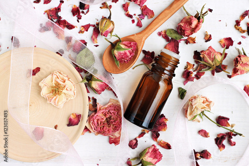 
Essential rose oil, dried rose petals, aroma dropper bottle, wooden preparation utensils. Natural beauty care. 