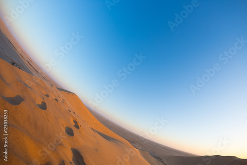 Scenic ridges of sand dunes with footprints in the Namib desert, tourist attraction in Namibia. Adventure and exploration in Africa. Fisheye oblique view.