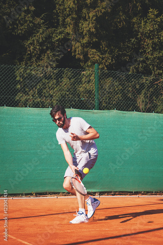 Young man playing tennis on the open court © marjan4782