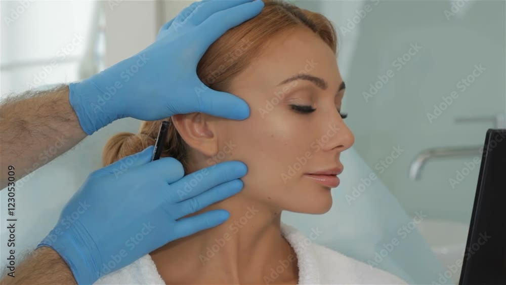 Cosmetologist stretches the skin on client's cheek Cosmetologist stretches the skin on client's cheek