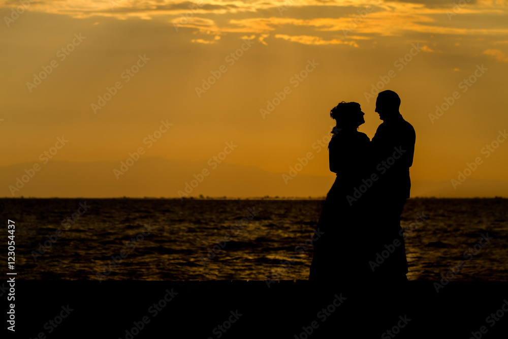Silhouette of a young bride and groom on Sunset background