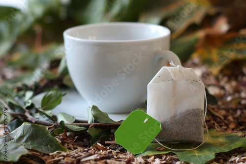 Teebeutel mit Teetasse im Hintergrund