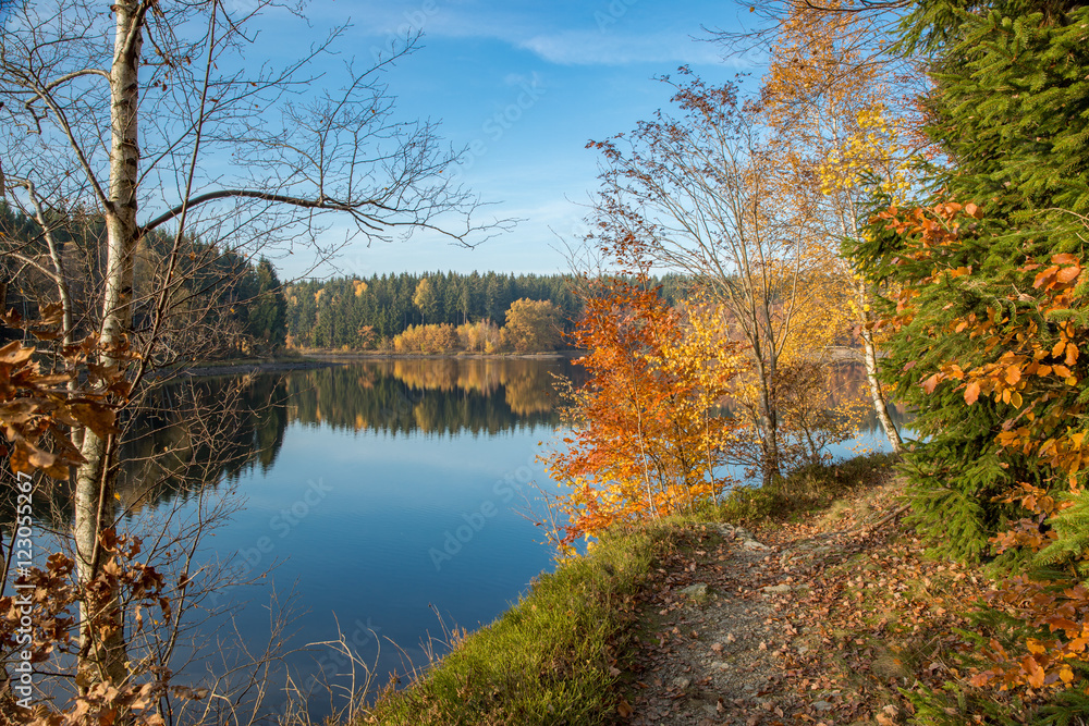 Spiegelungen der Herbstfärbung im blauen Wasser am Frankenteich im Südharz