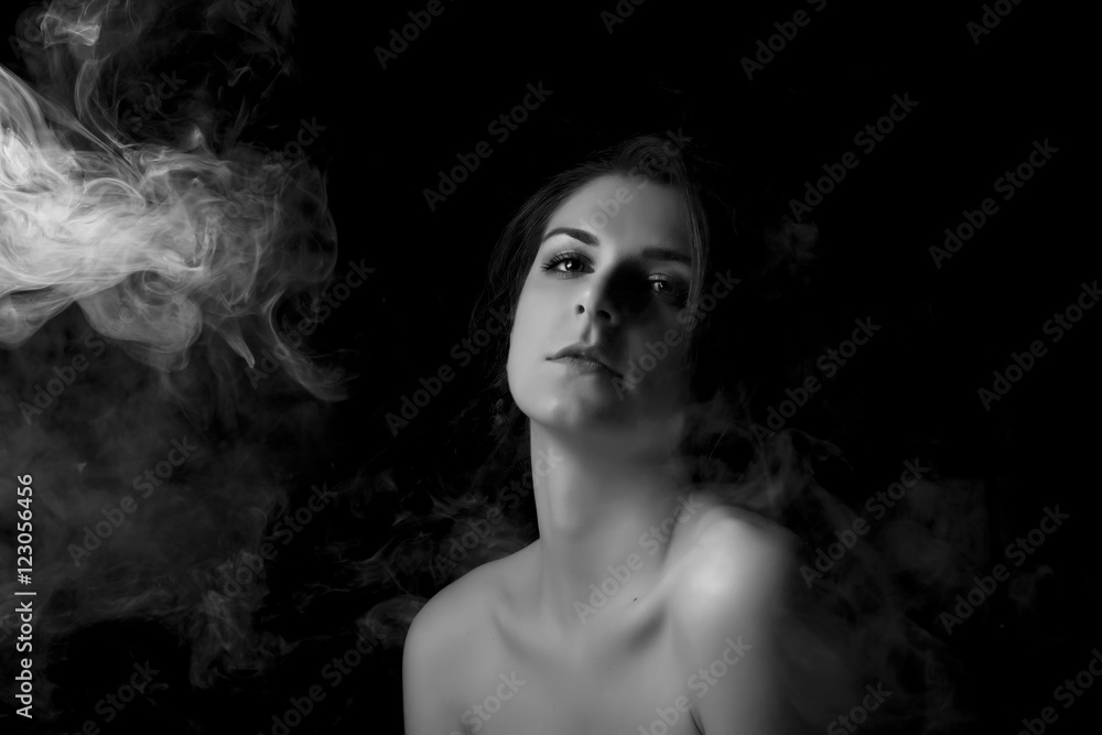 Woman blowing smoke against black background.