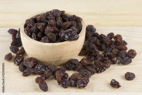 raisins in bowl on wooden table.