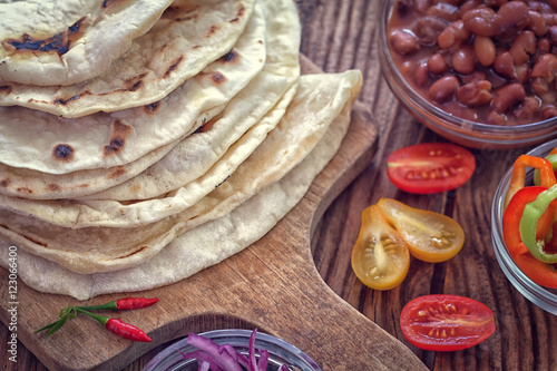 Mexican corn tortilla tacos with vegetables on wooden background 