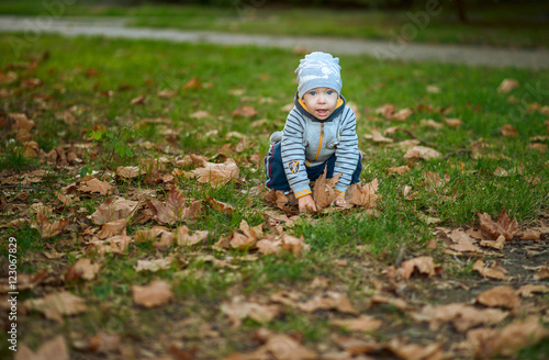 мальчик сидит на корточках в листьях