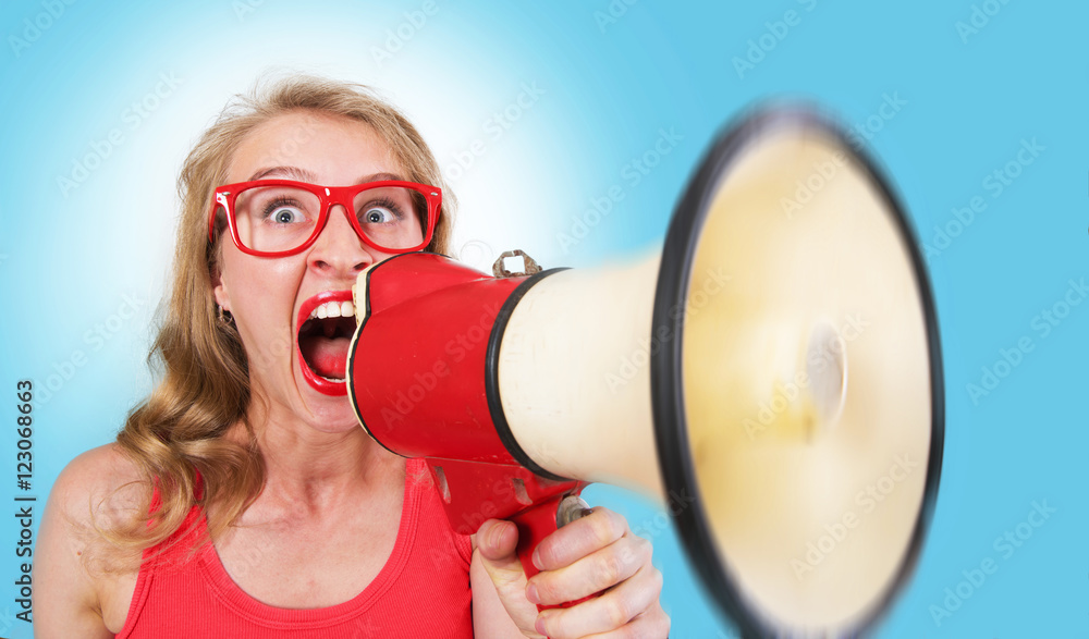 Naklejka premium Funny portrait of a girl shouting through the megaphone