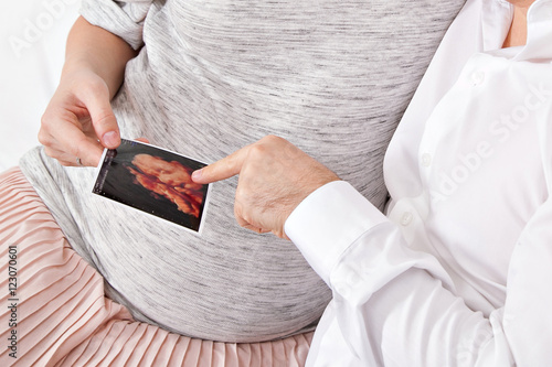 pregnant woman's belly, mom and dad holding ultrasound picture