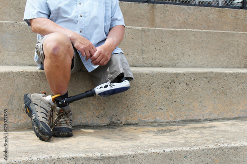 Fotografie Amputee with legs crossed sitting on concrete bleachers