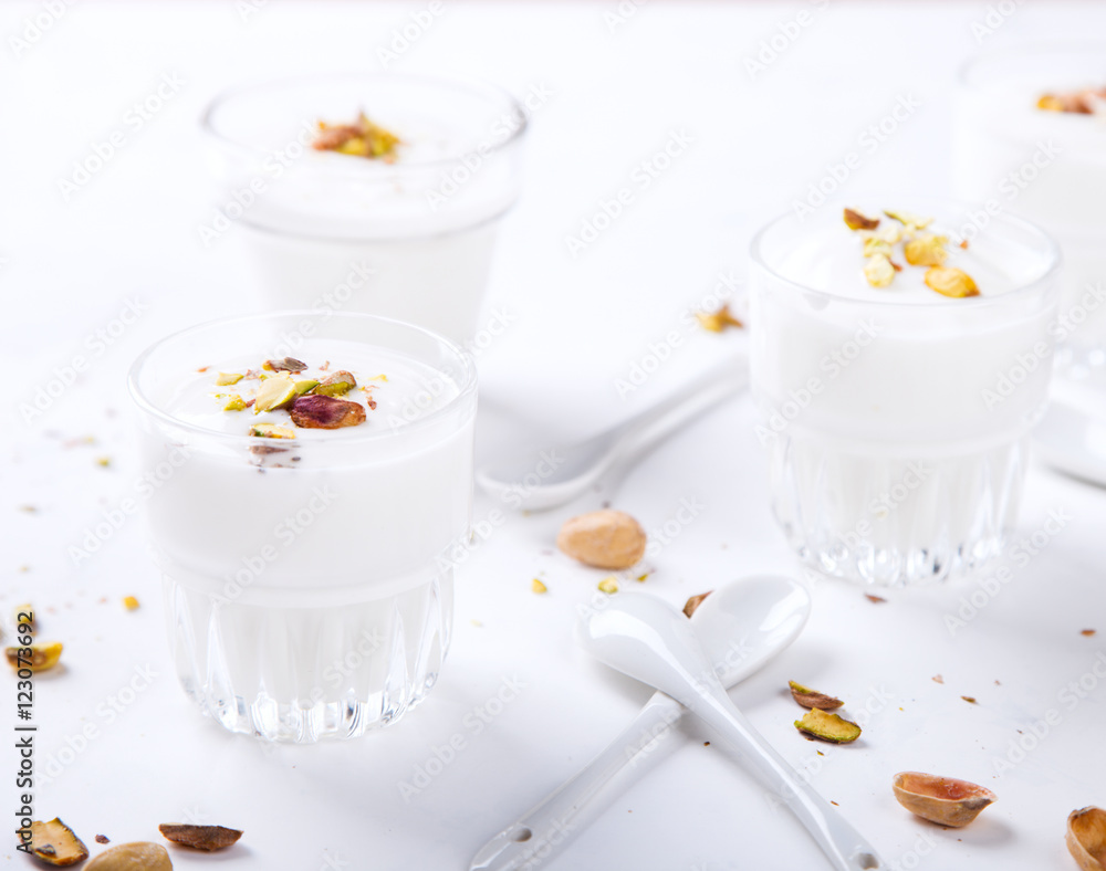 Yogurt in glass cups with nuts,pistachios.Breakfast,Dessert, Pudding on a white background.Food or Healthy diet concept.selective focus.Top view. Yogurt in glass cups with nuts,pistachios.Breakfast,Dessert, Pudding on a white background.Food or Healthy diet concept.selective focus.Top view.