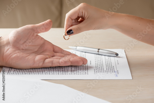 Wife and husband signing divorce documents, woman returning wedding ring photo