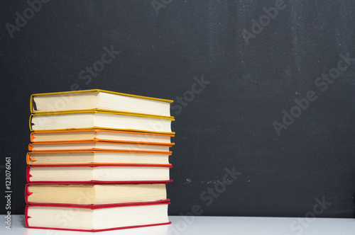 pile of colorful books on blackboard background