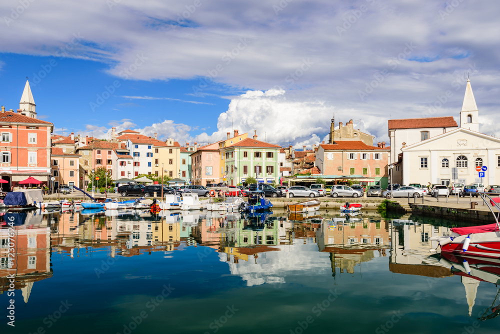 the scenic harbour with boats and brightly coloured houses on the waterfront in Izola, Slovenia.