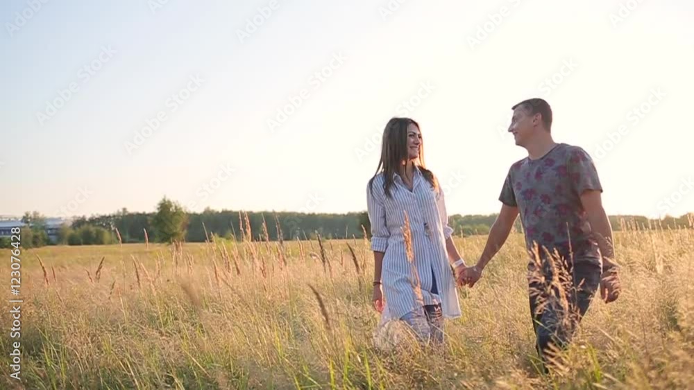 couple walking holding hands in the grass field. couple walking holding hands in the grass field.