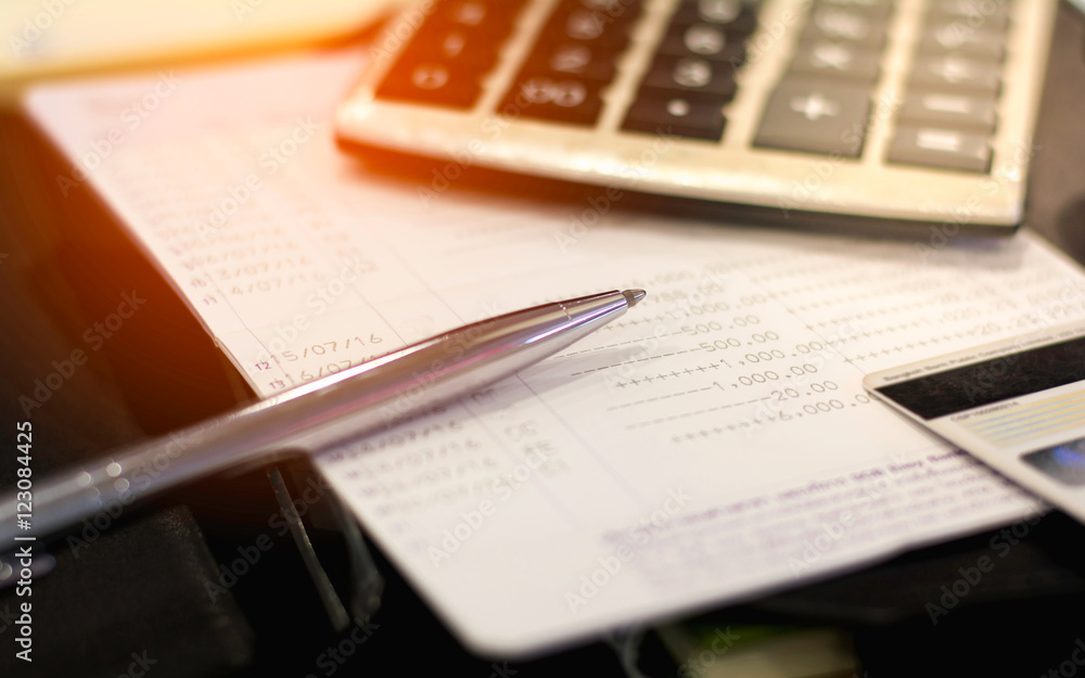 Obraz premium Blurred bookbank and pen with calculator and credit card on notebook, vintage tone.