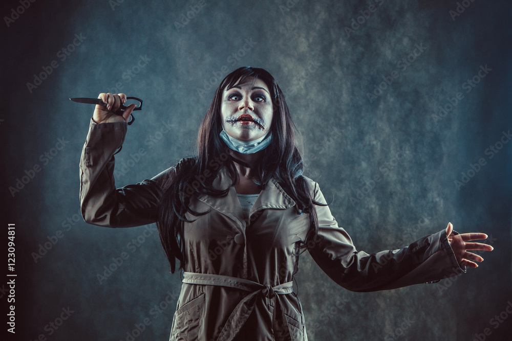Zombie girl with the broken mouth with the scissors in a hand. Zombie girl with the broken mouth with the scissors in a hand.